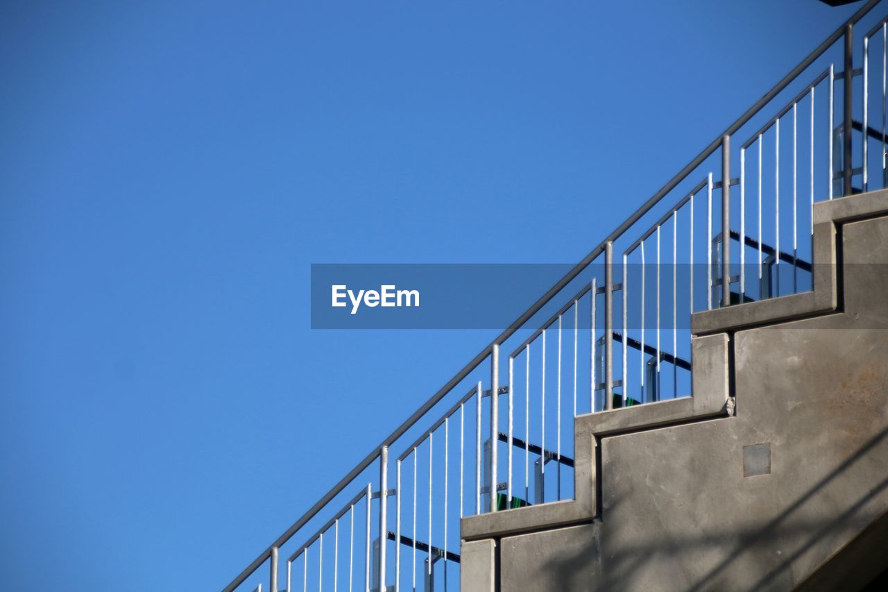 Low angle view of staircase by building against clear blue sky