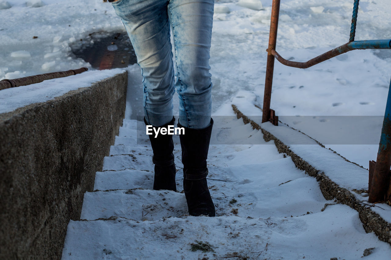 Low section of woman walking on snowy steps