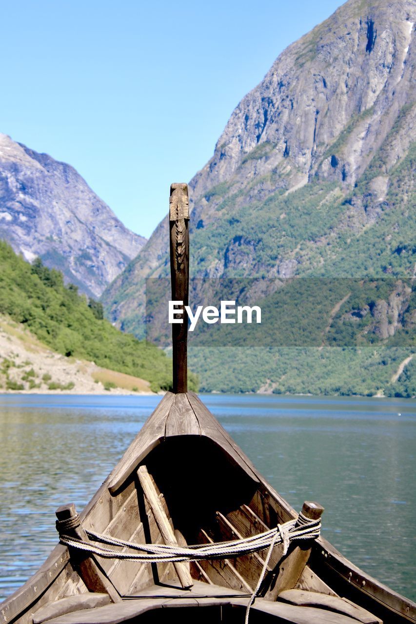 Wooden viking ship by fjord against mountain range