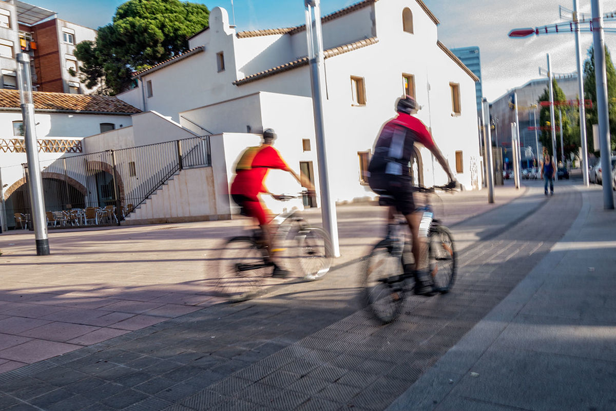 Men cycling on street against houses