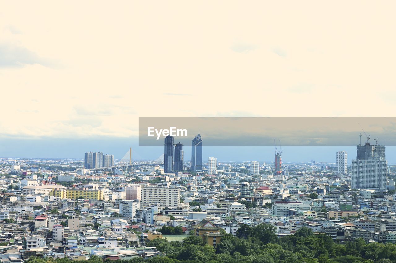 View of cityscape against cloudy sky