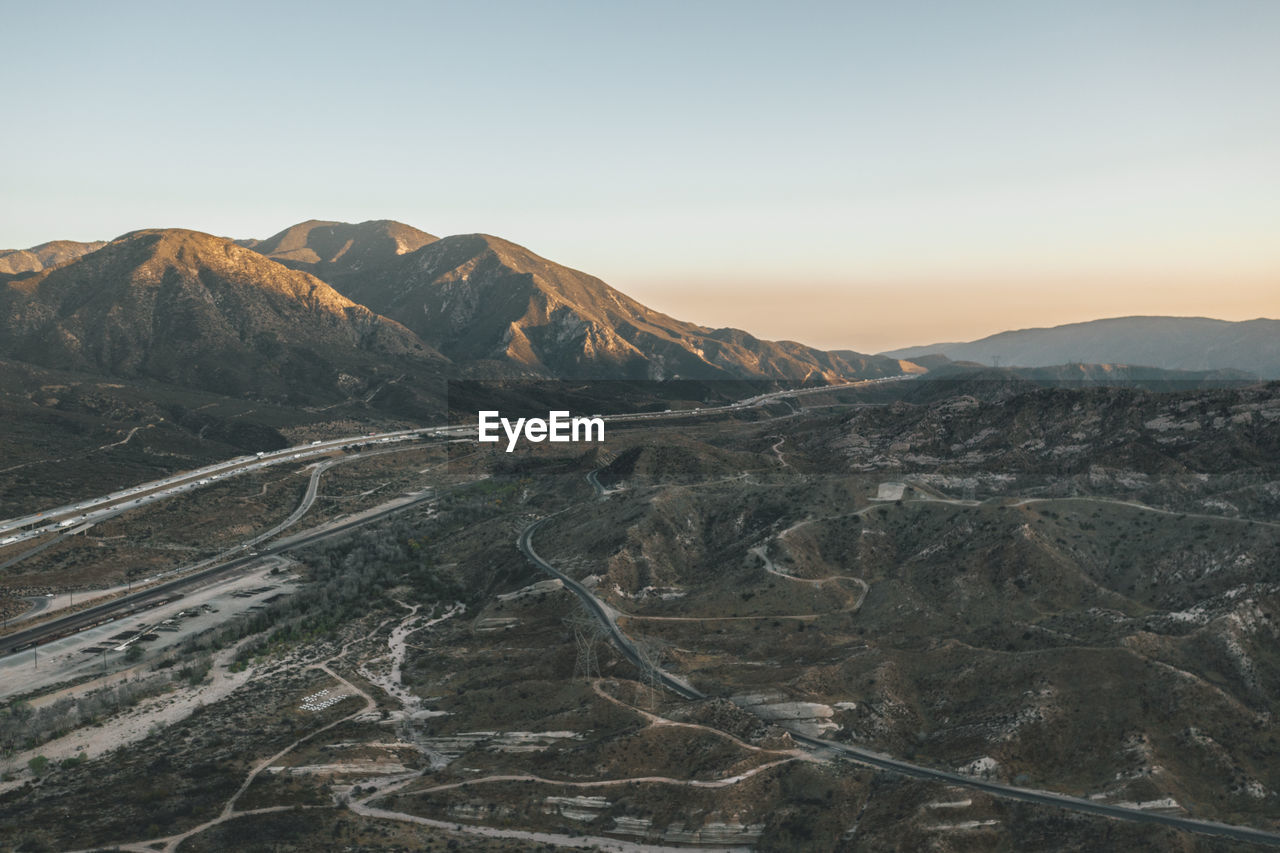 Aerial view over california country site desert mountains with highway and car traffic