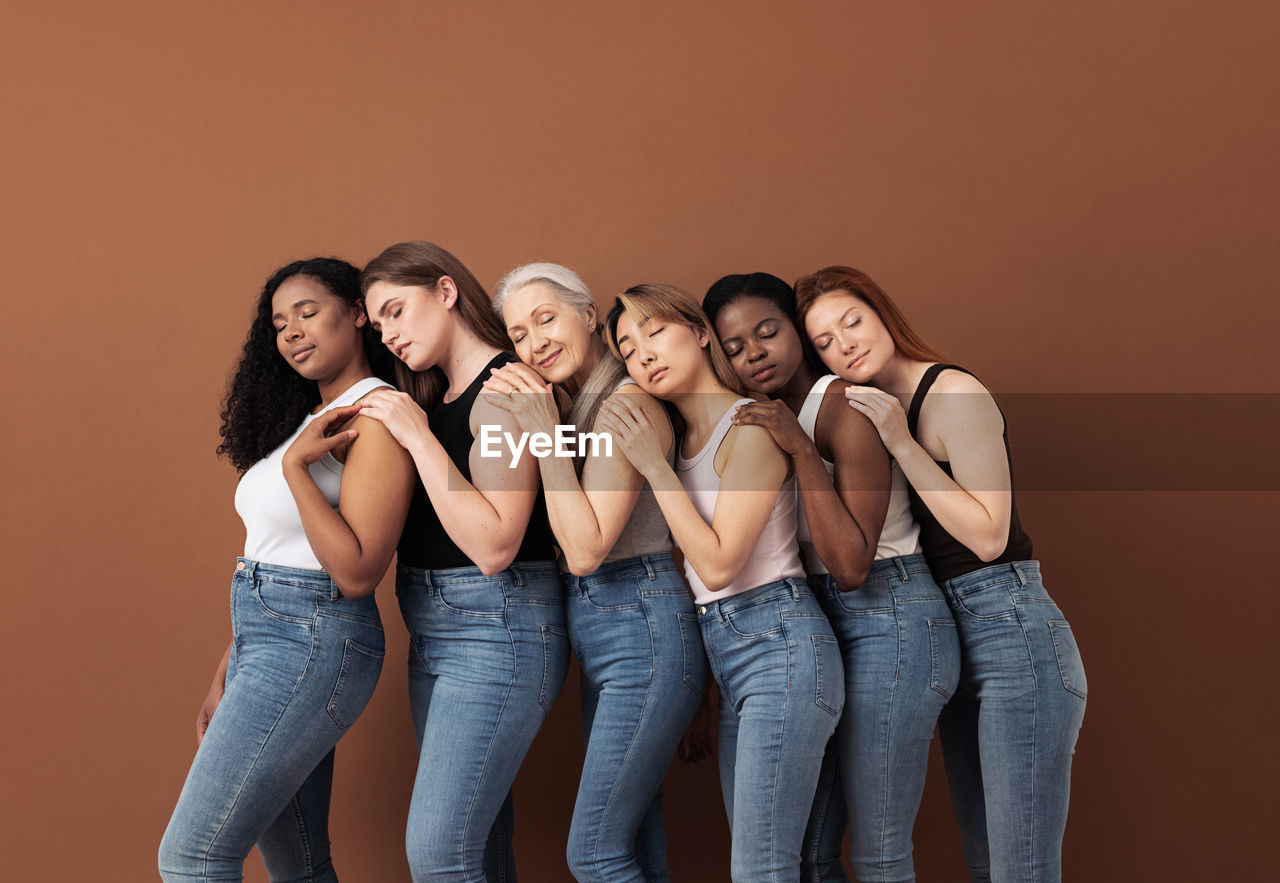 Women standing against brown background