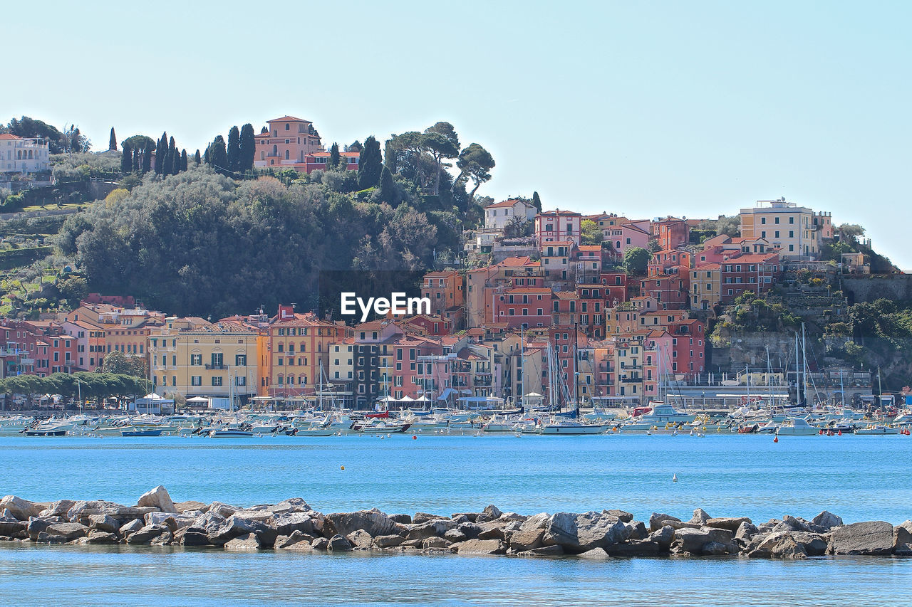 Sea by buildings against clear sky