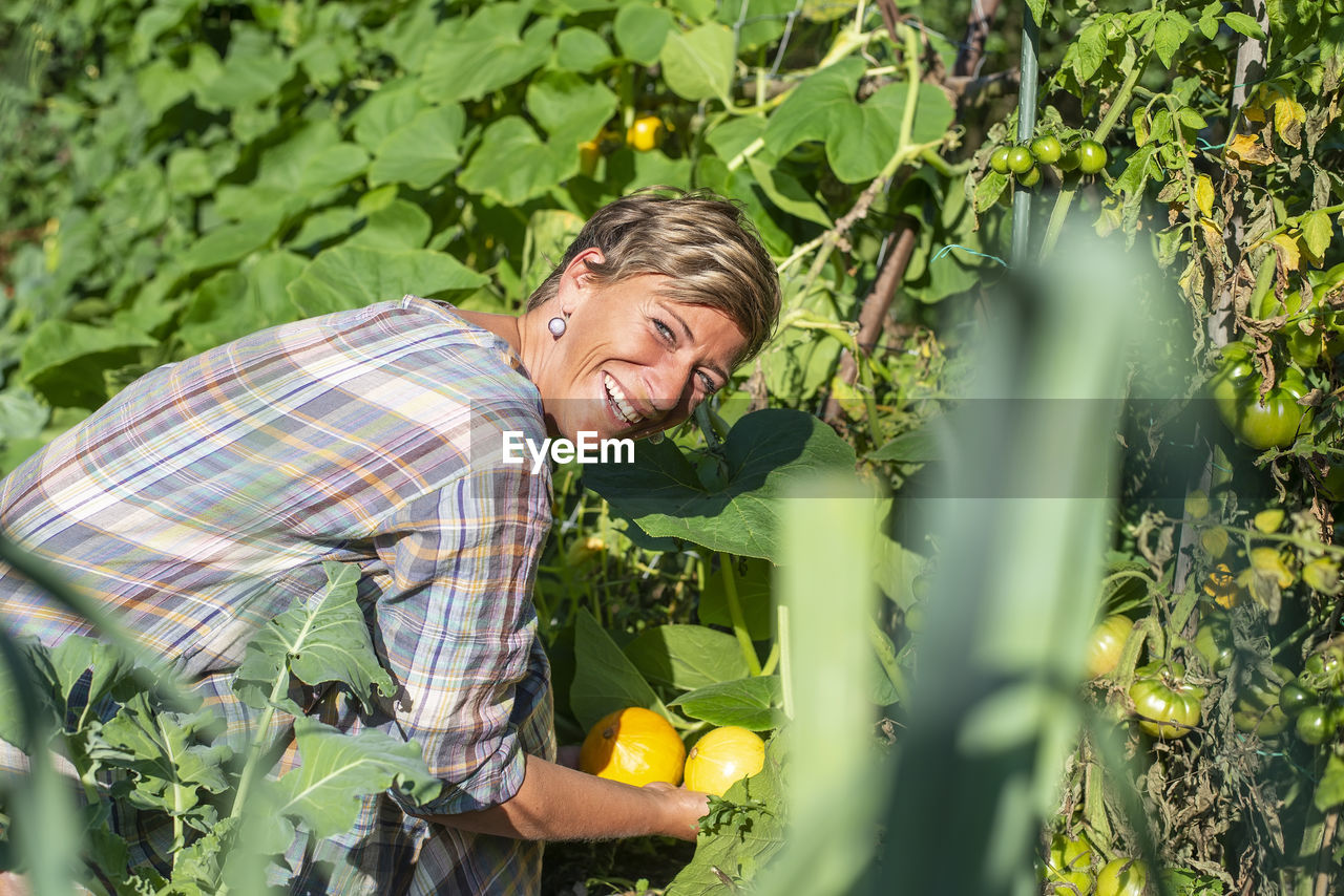 Portrait of smiling woman holding fruits at farm