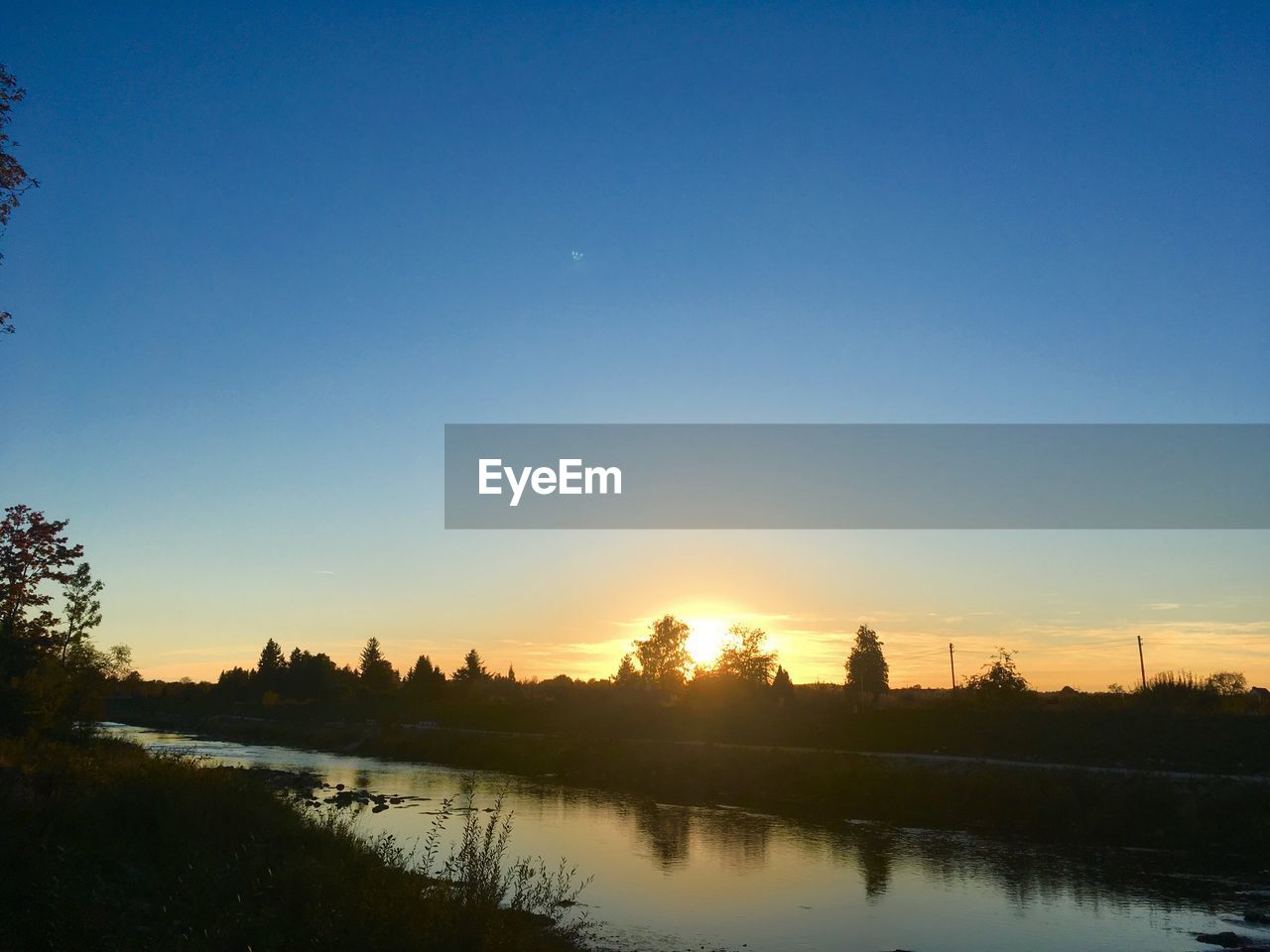 SCENIC VIEW OF LAKE AGAINST CLEAR SKY AT SUNSET