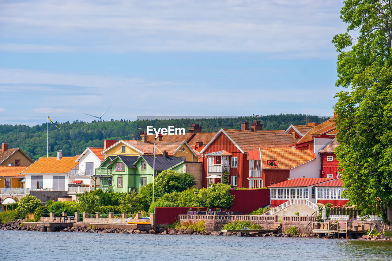 Houses by river and buildings against sky