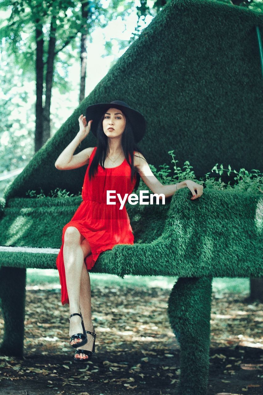 Portrait of young woman sitting on piano shaped bench