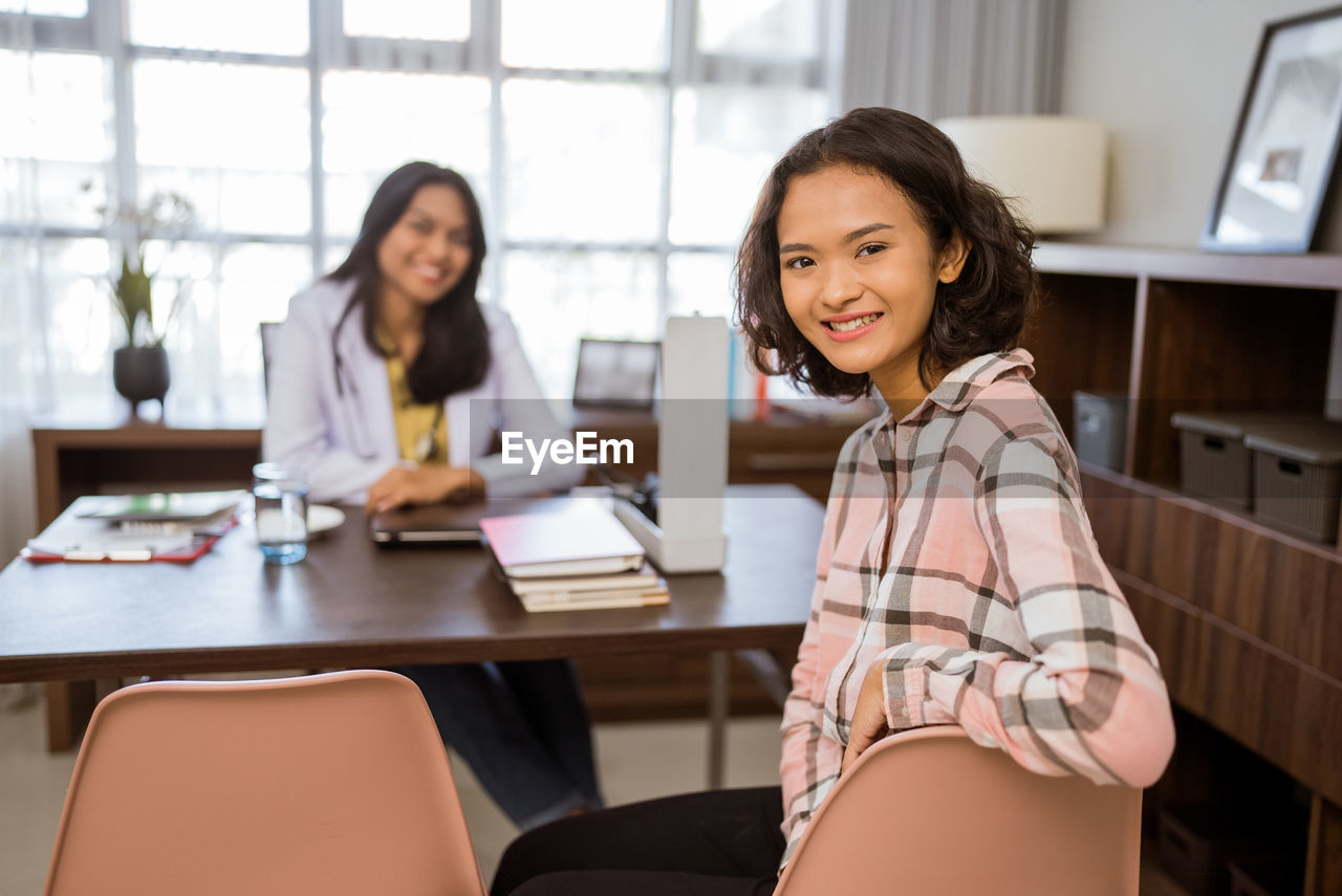 portrait of young woman sitting on table at office