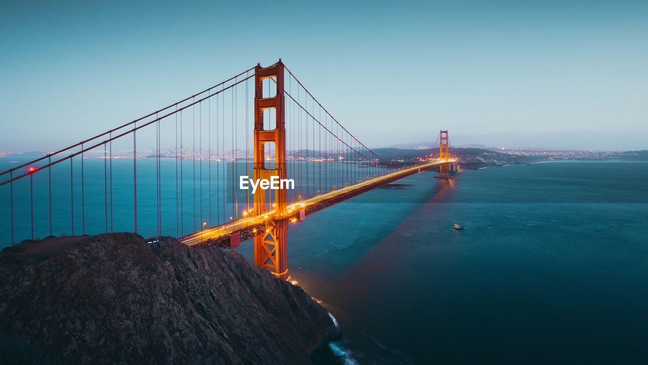 Golden gate bridge over sea against clear sky during sunset