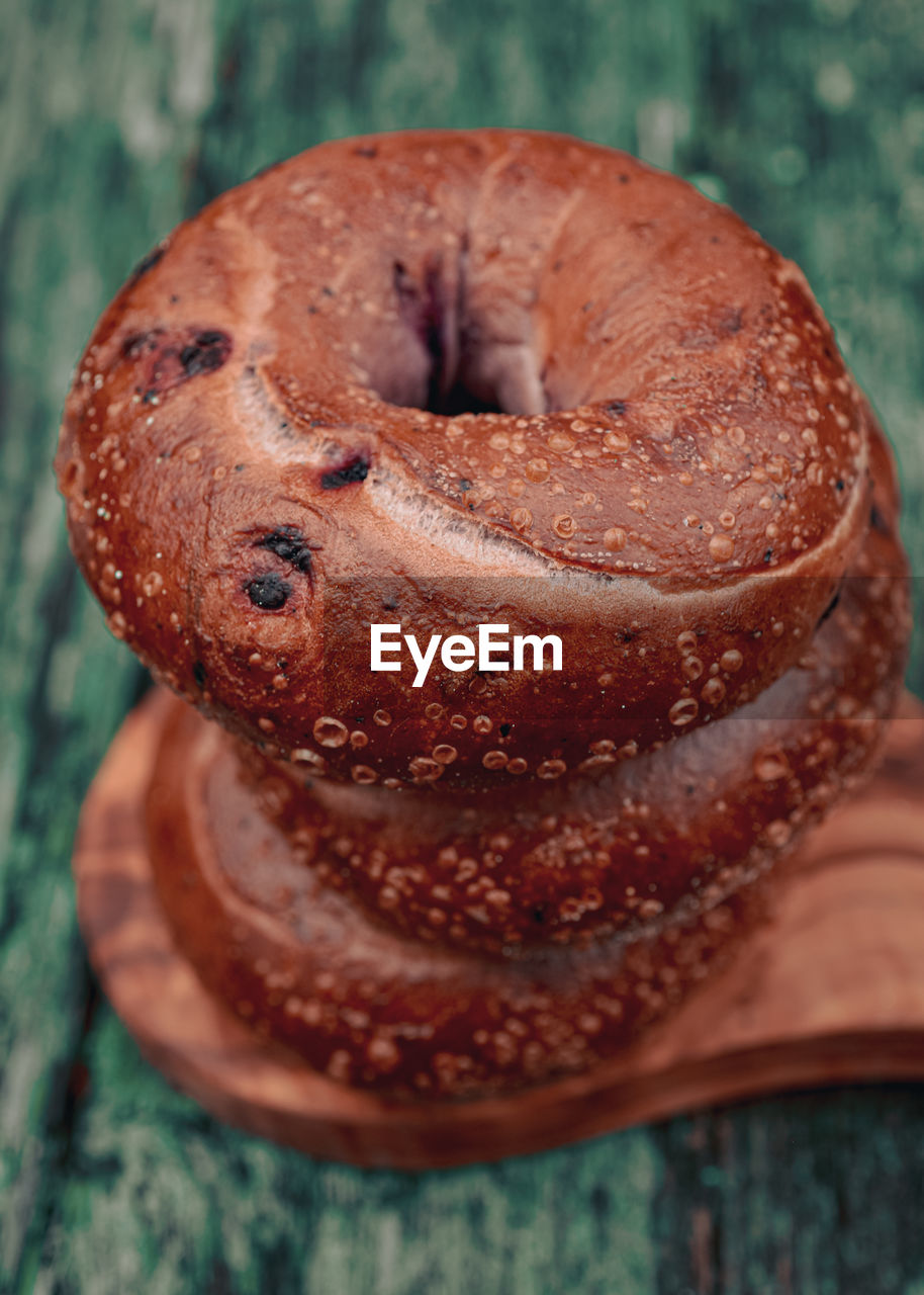 Top view of stack of three blueberry bagels on small olive wood cutting board