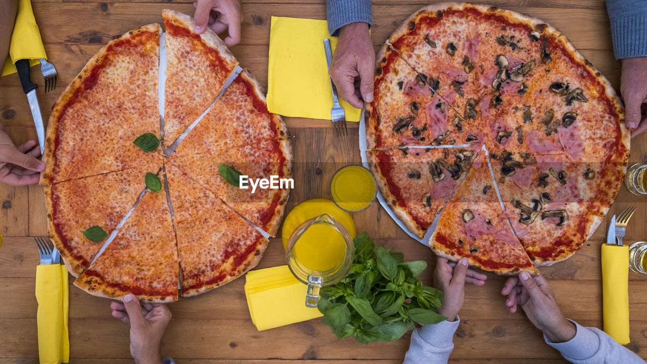 HIGH ANGLE VIEW OF HAND HOLDING PIZZA