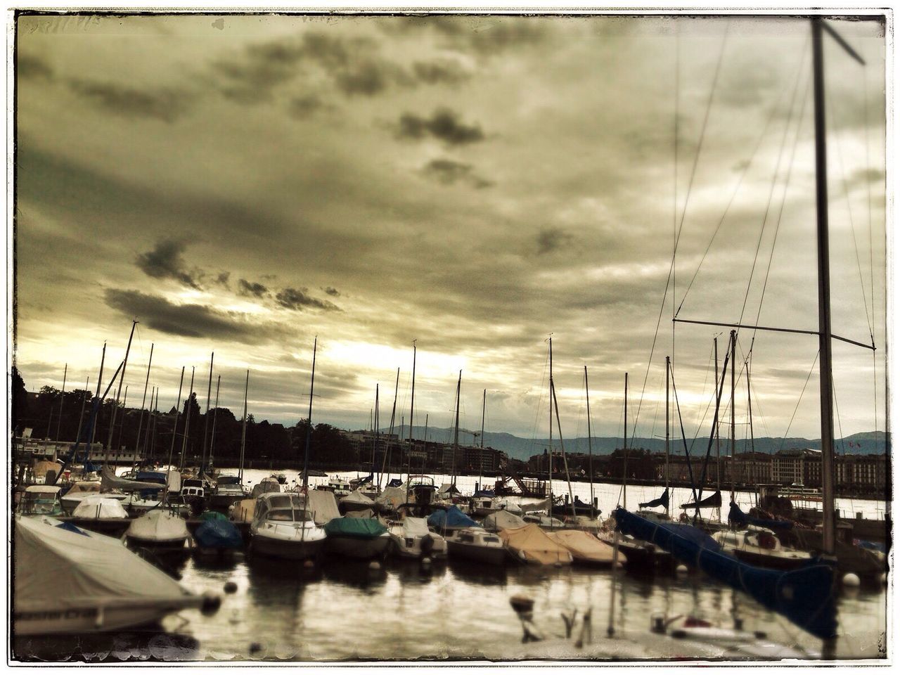 BOATS IN HARBOR AGAINST CLOUDY SKY