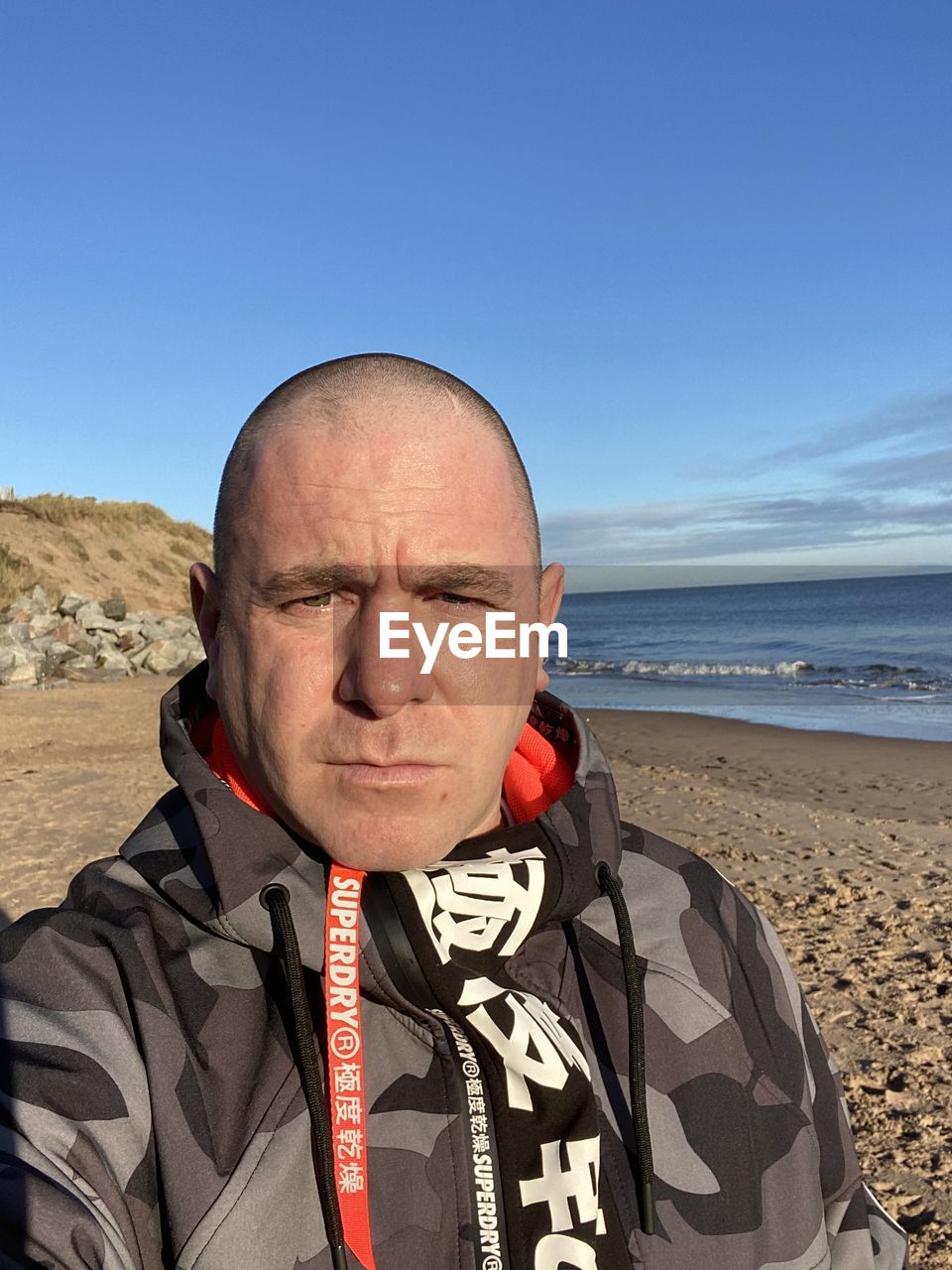 PORTRAIT OF MAN WEARING SUNGLASSES ON BEACH