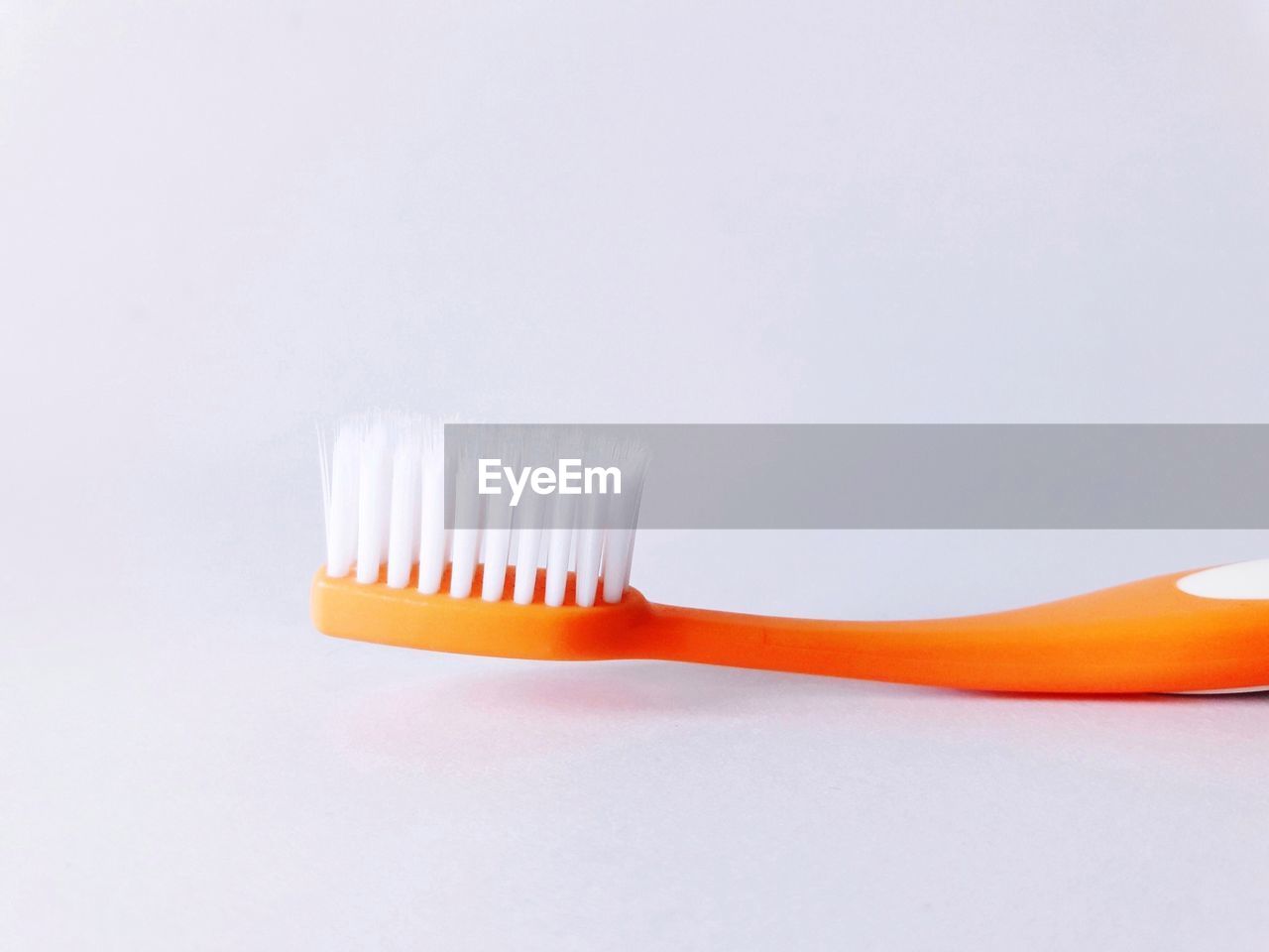 Close-up of orange toothbrush against gray background