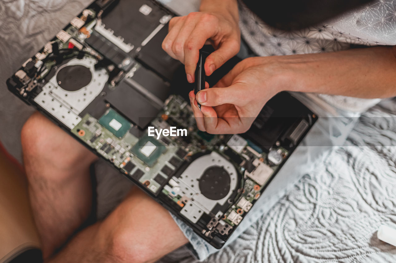 A young man is changing the thermal paste on a laptop.