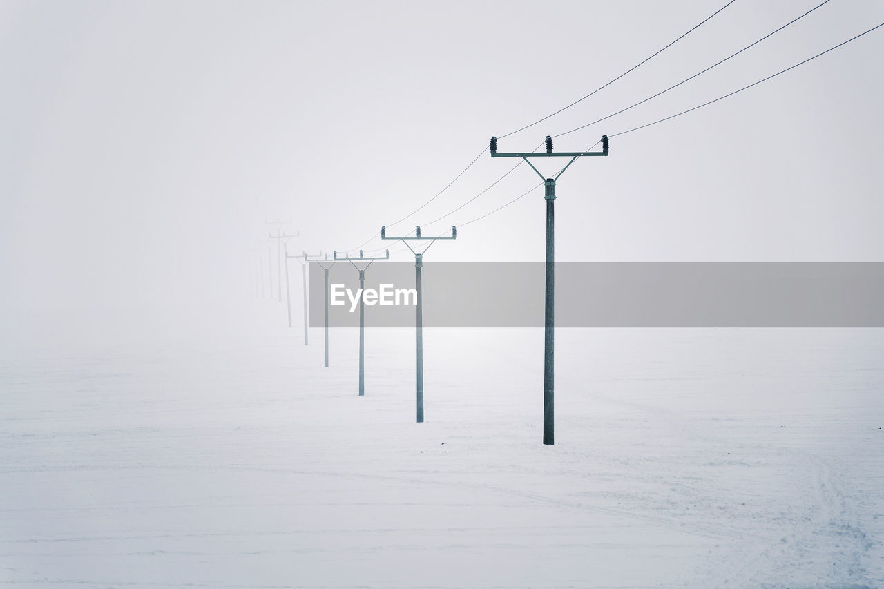 Electricity pylons from distribution power station disappearing in deep fog