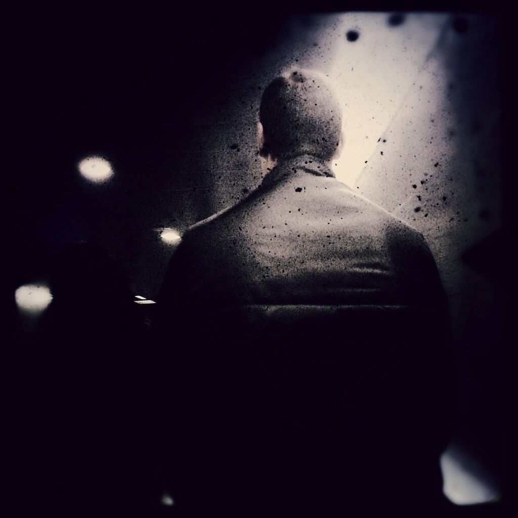 Rear view of man sitting in a dark room