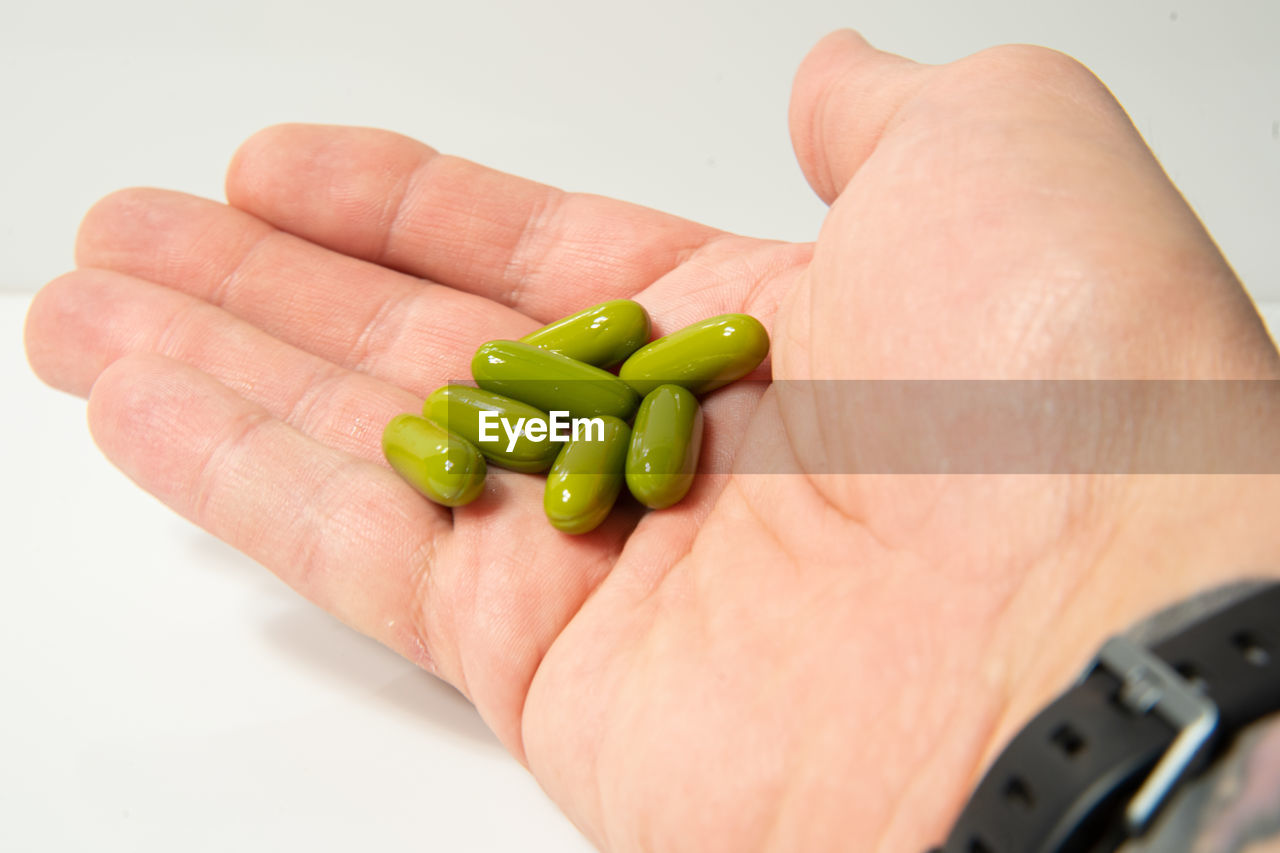 CROPPED IMAGE OF PERSON HOLDING GREEN CHILI PEPPER