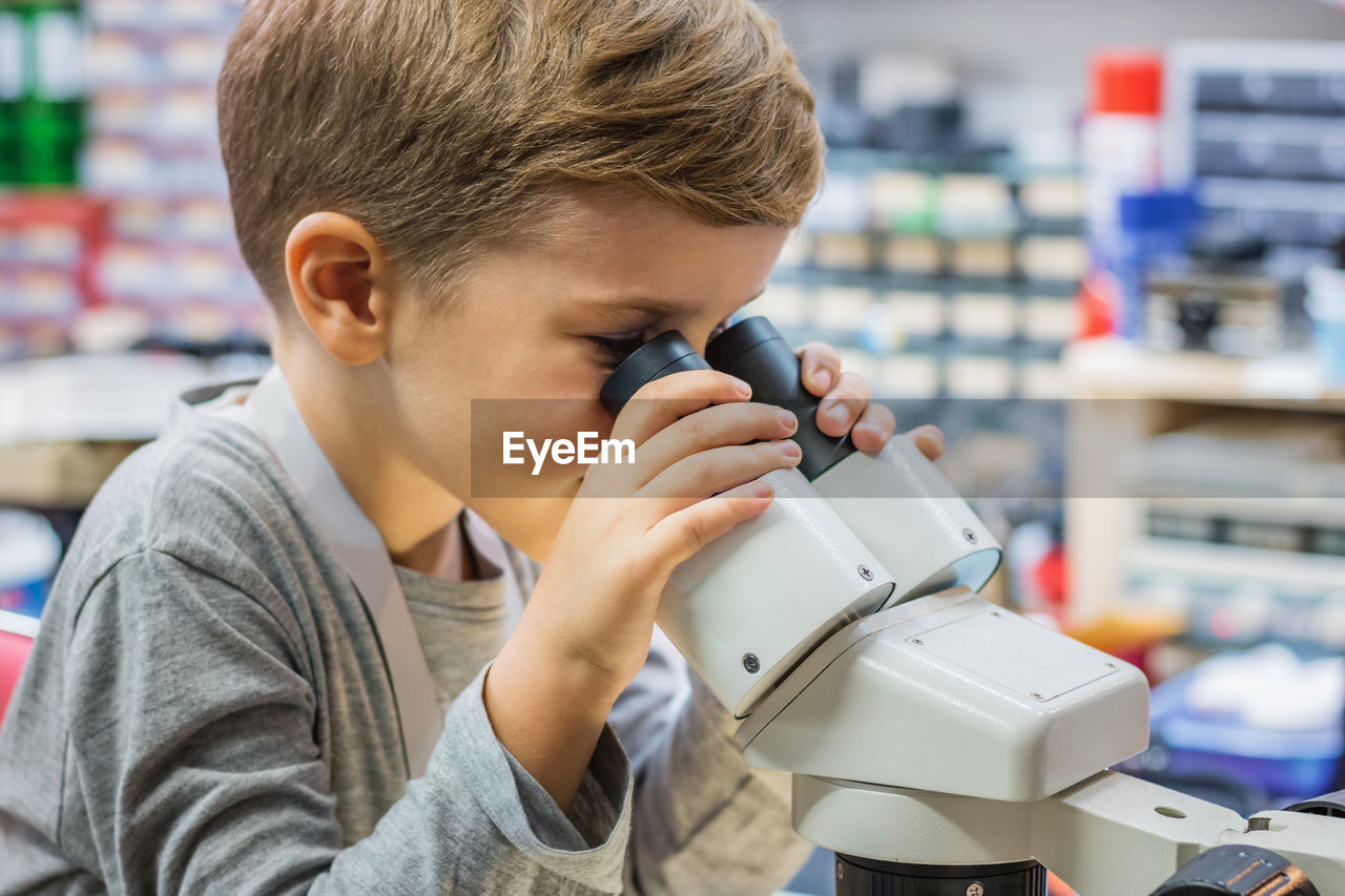 Side view of boy looking through microscope in laboratory