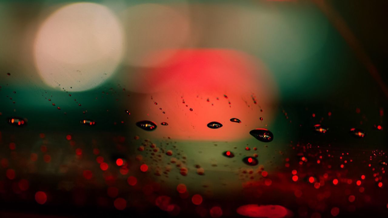 CLOSE-UP OF WATER DROPS ON ILLUMINATED RED LIGHTS