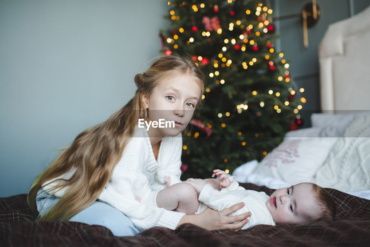 portrait of smiling young woman sitting on christmas tree