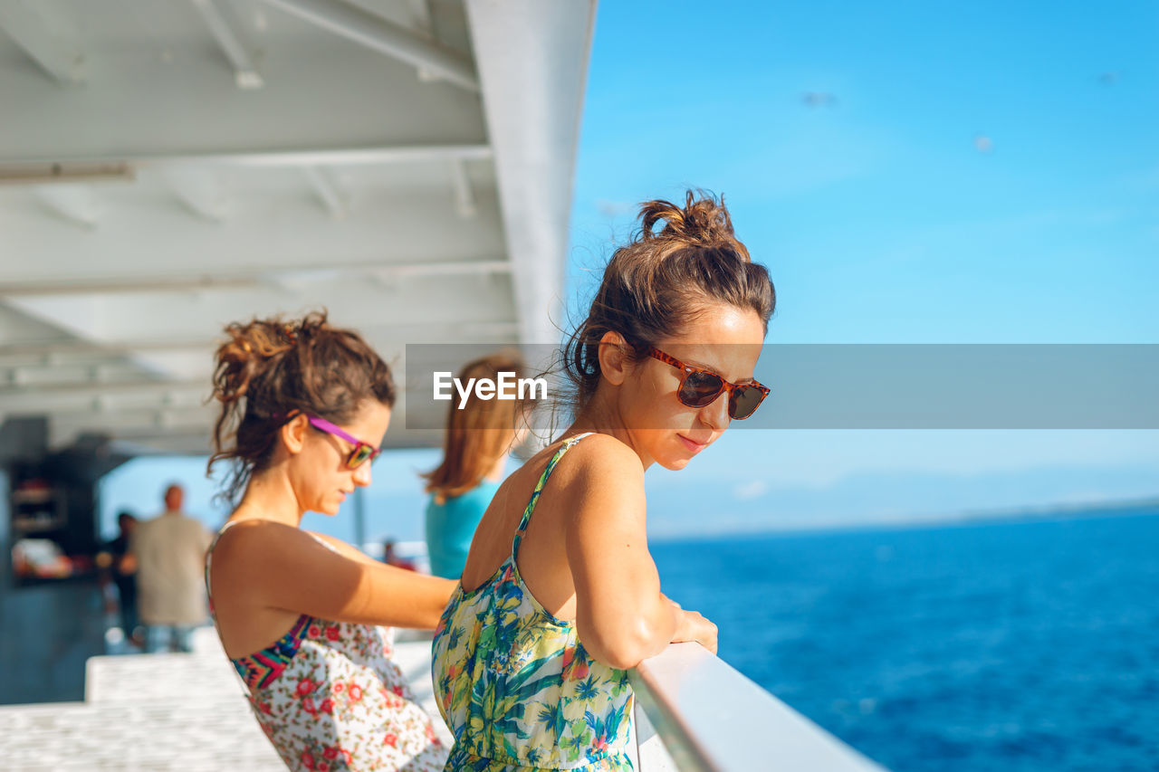 Young women spending leisure time on boat deck against sky