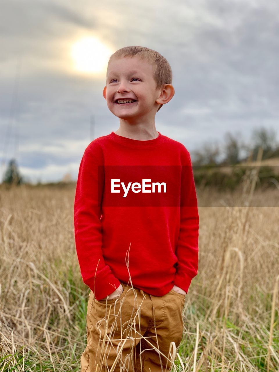 Cute smiling boy looking away while standing by plants on land