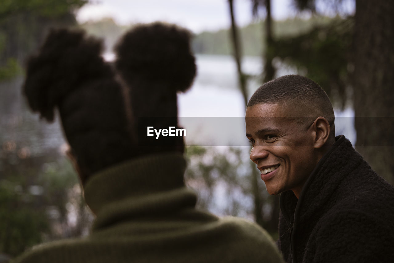 Smiling man talking to friend in forest