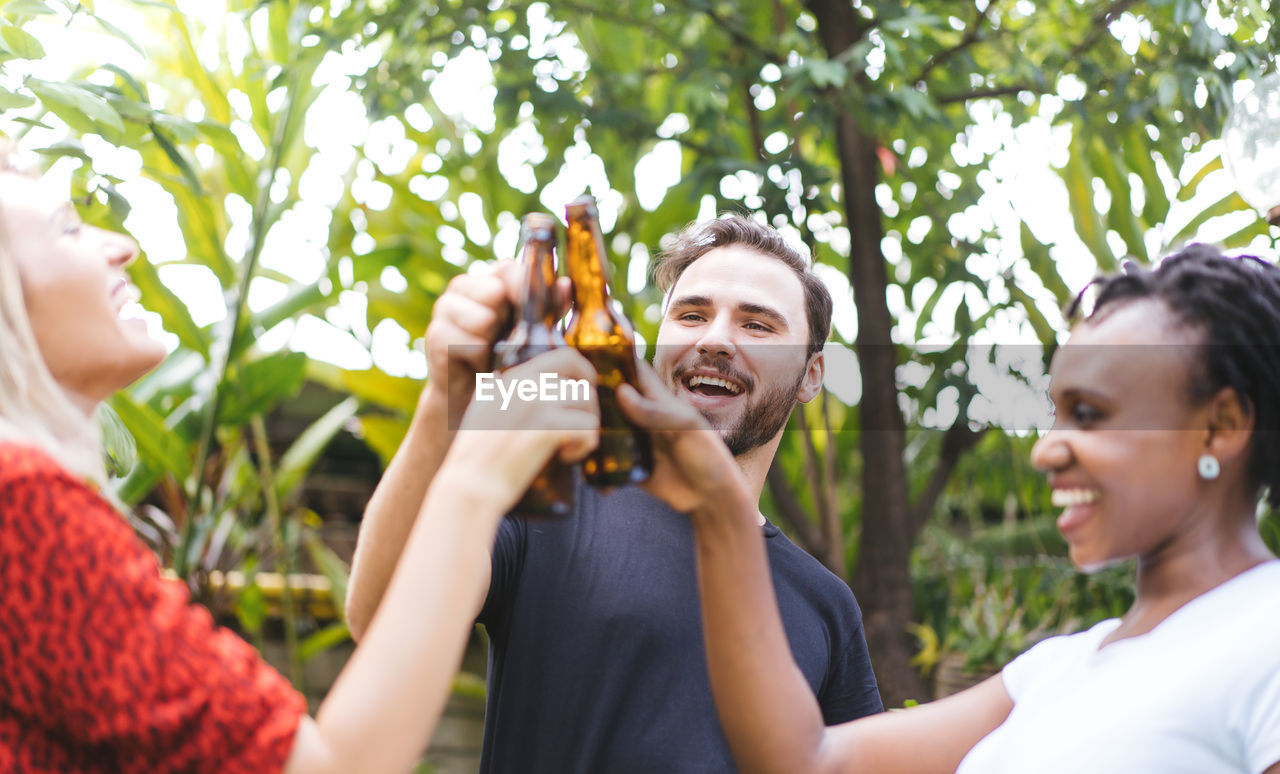 Happy friends toasting beer bottles