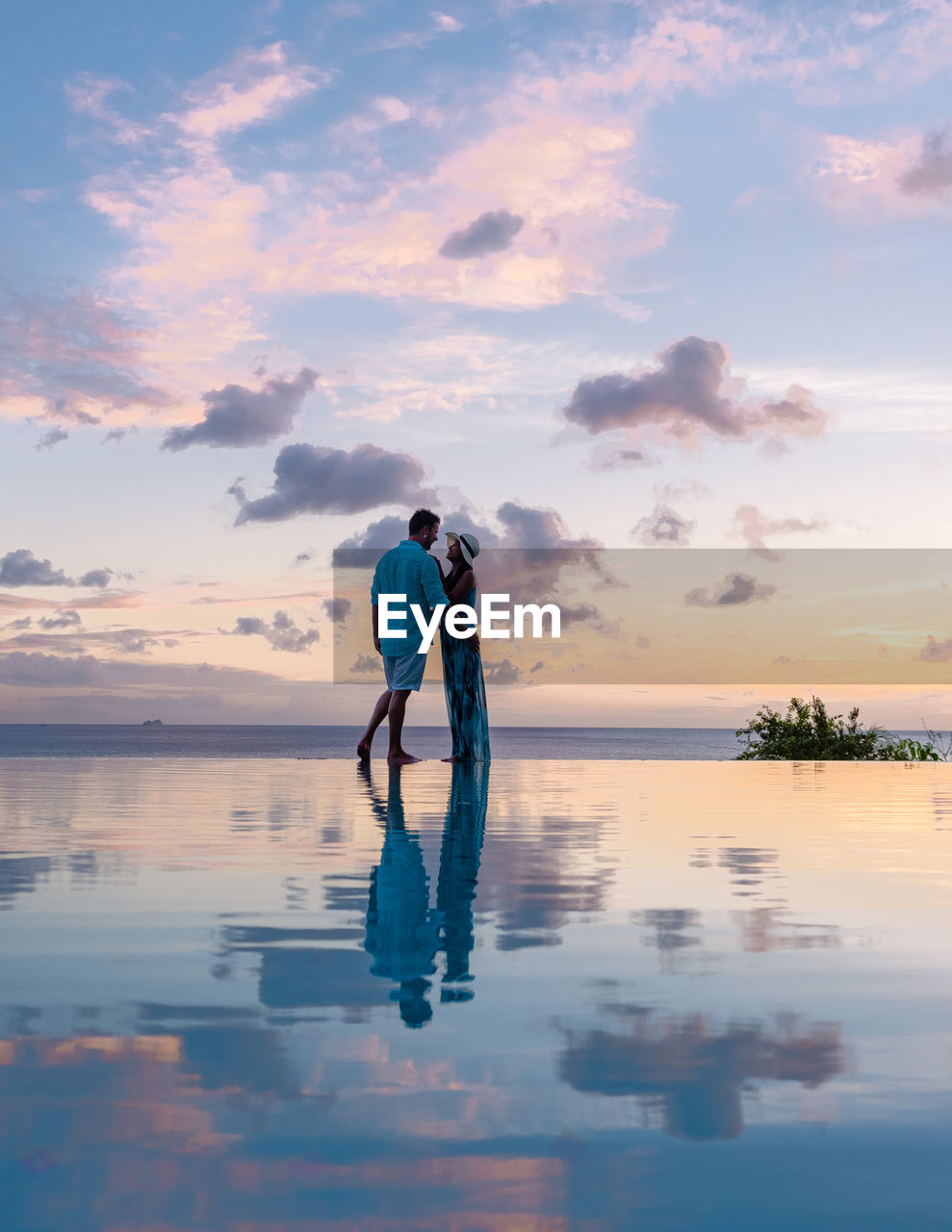 rear view of man walking on beach against sky during sunset