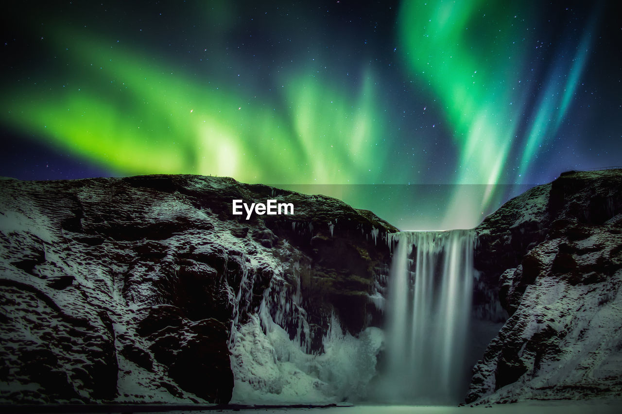 Scenic view of waterfall against aurora during night