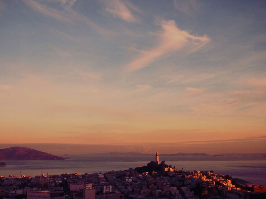 Aerial view of city and sea against sky during sunset