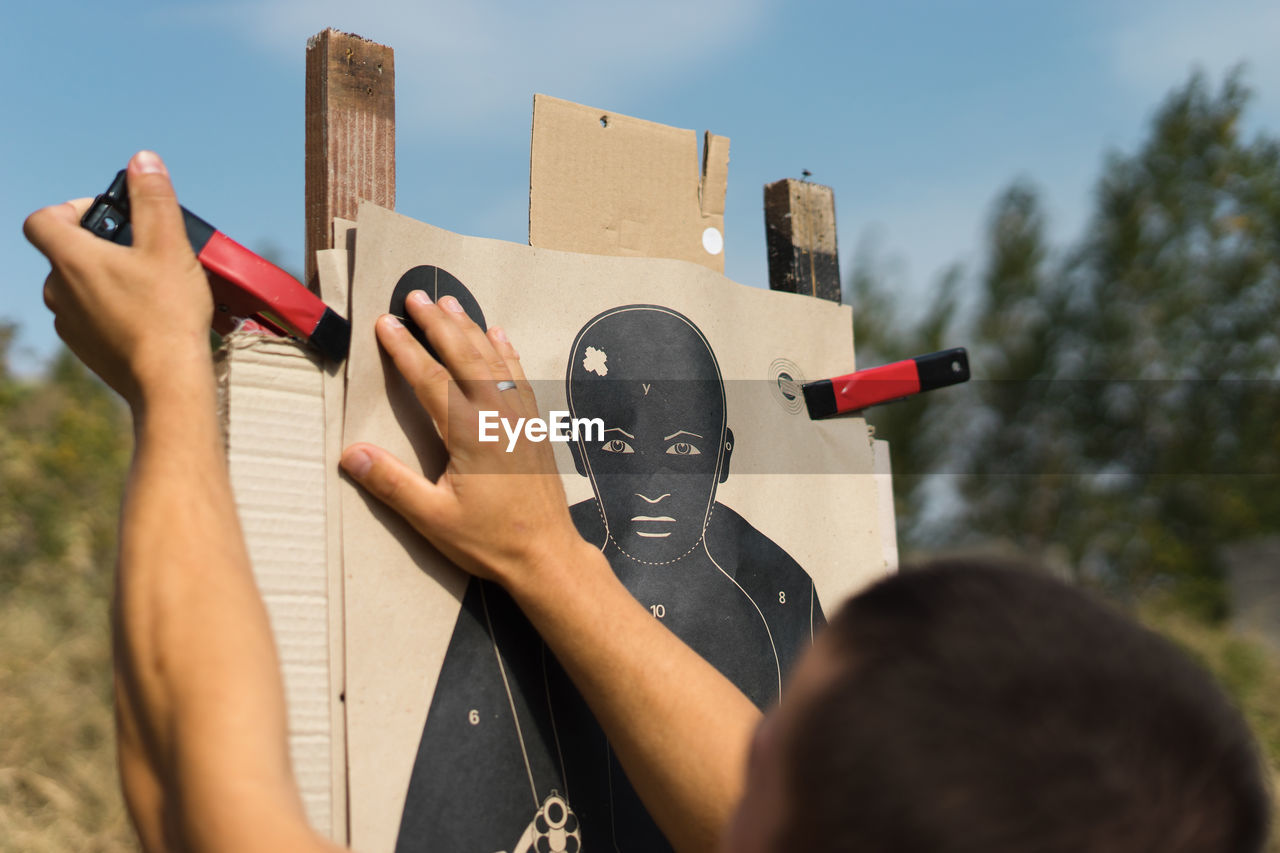 Cropped image of man adjusting clamp on shooting target