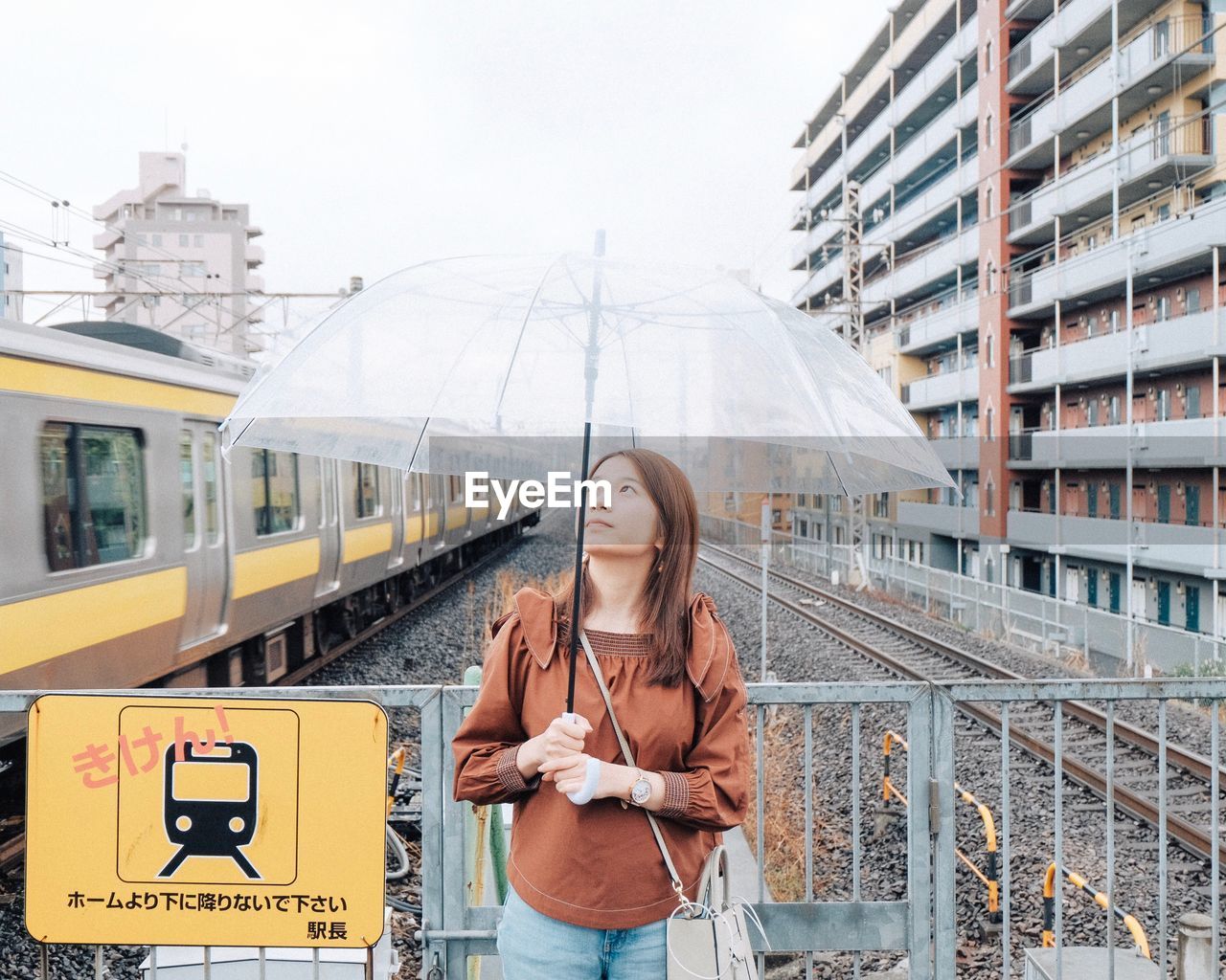 YOUNG WOMAN WITH UMBRELLA ON CITY STREET