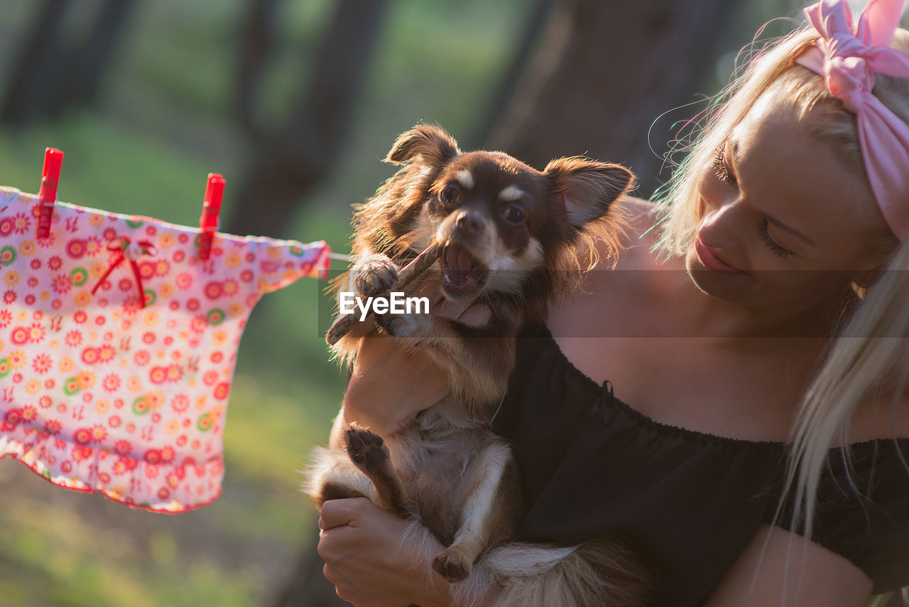 Close-up of smiling woman carrying chihuahua