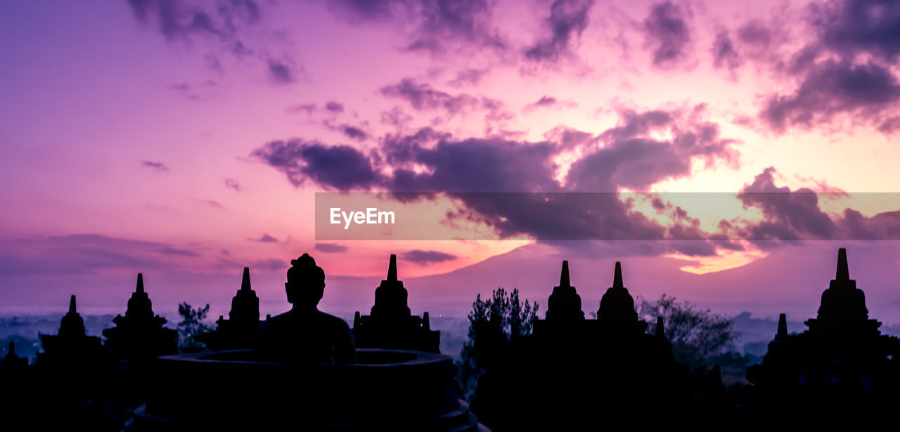 Silhouette buddha statue against sky during sunset