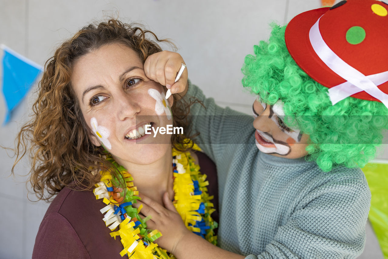 Mother painting her son's face like a clown