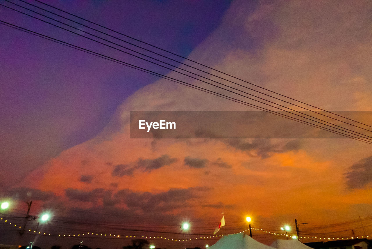 LOW ANGLE VIEW OF ILLUMINATED BUILDINGS AGAINST SKY AT SUNSET