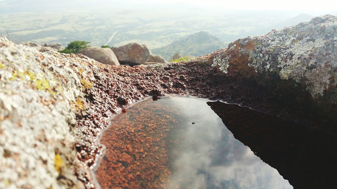 Close-up of water collected amidst rock against landscape
