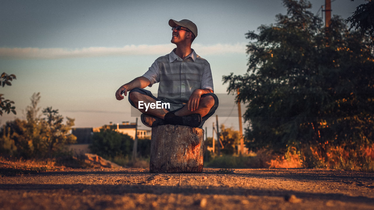 YOUNG MAN STANDING AGAINST TREES