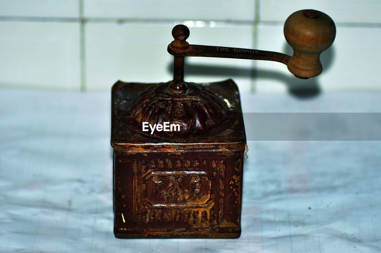 Close-up of old-fashioned coffee grinder against wall