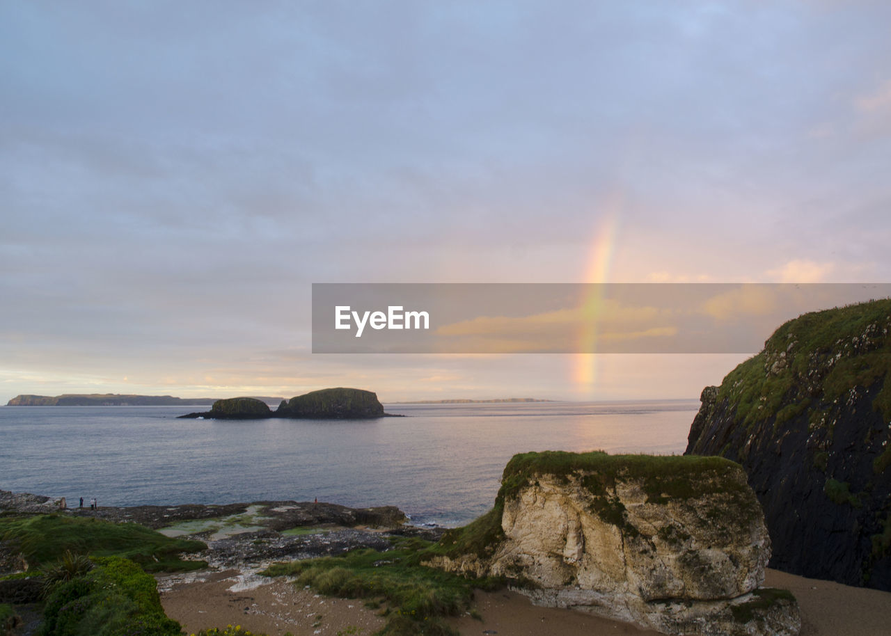 Scenic view of rainbow in sky on sea during sunset