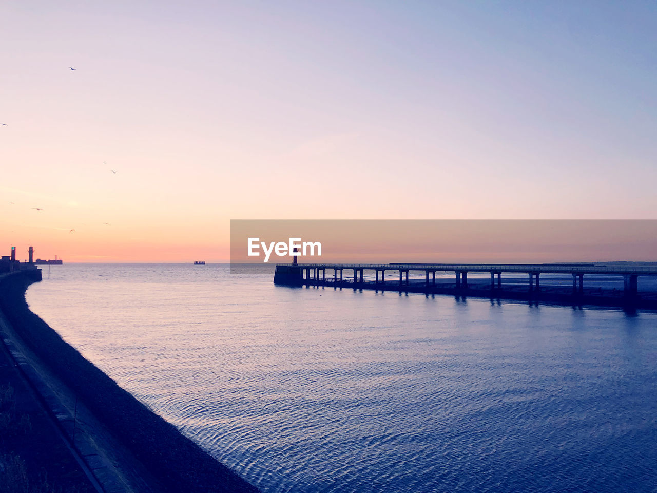 PIER ON SEA AGAINST CLEAR SKY DURING SUNSET