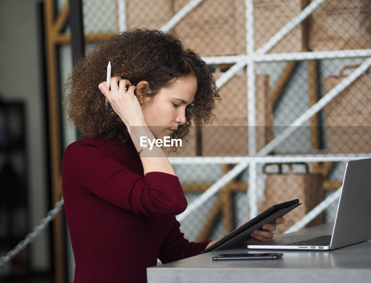 Portrait of a young beautiful serious woman with curly hair working in cafe.