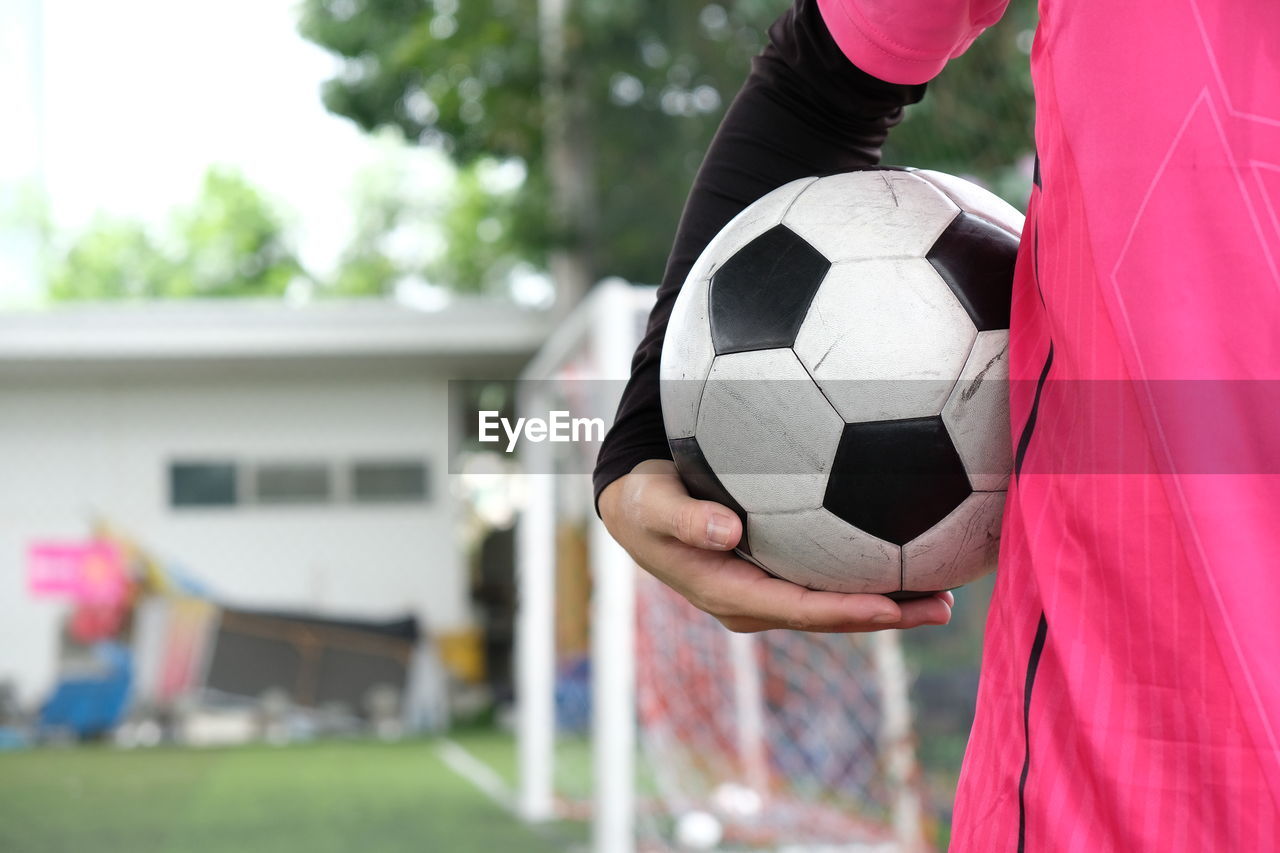 LOW SECTION OF MAN PLAYING SOCCER BALL ON FIELD