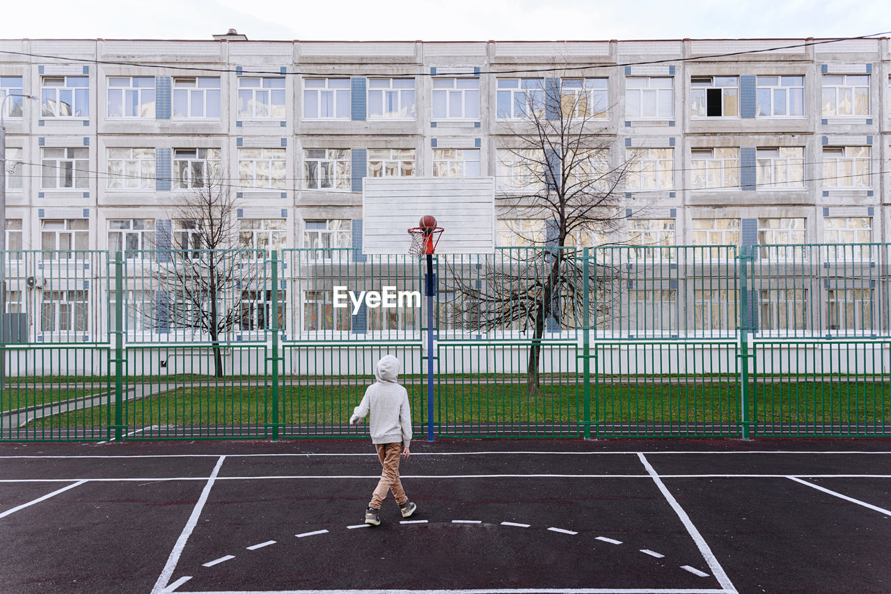 Teenager playing basketball on sport field