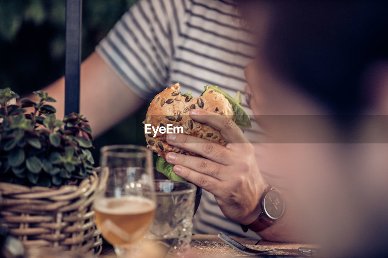 Midsection of man having burger in restaurant