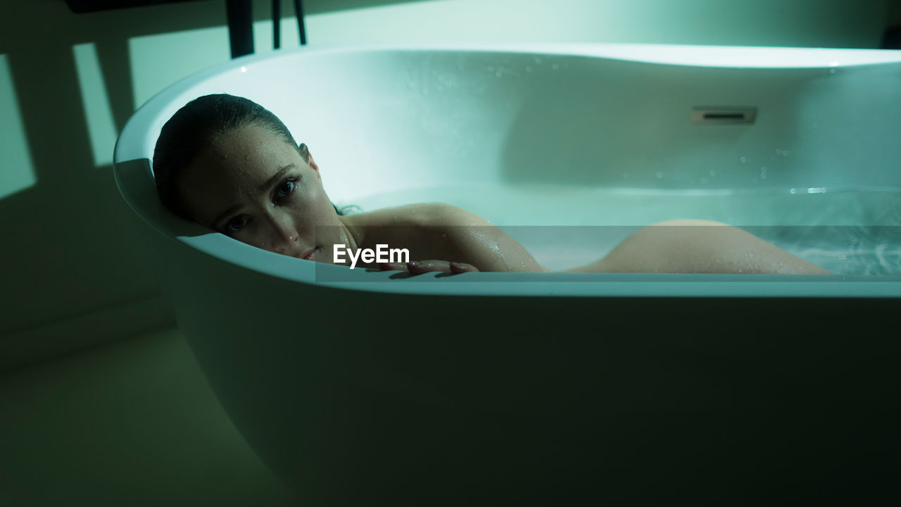 Low section of woman washing hands in bathtub