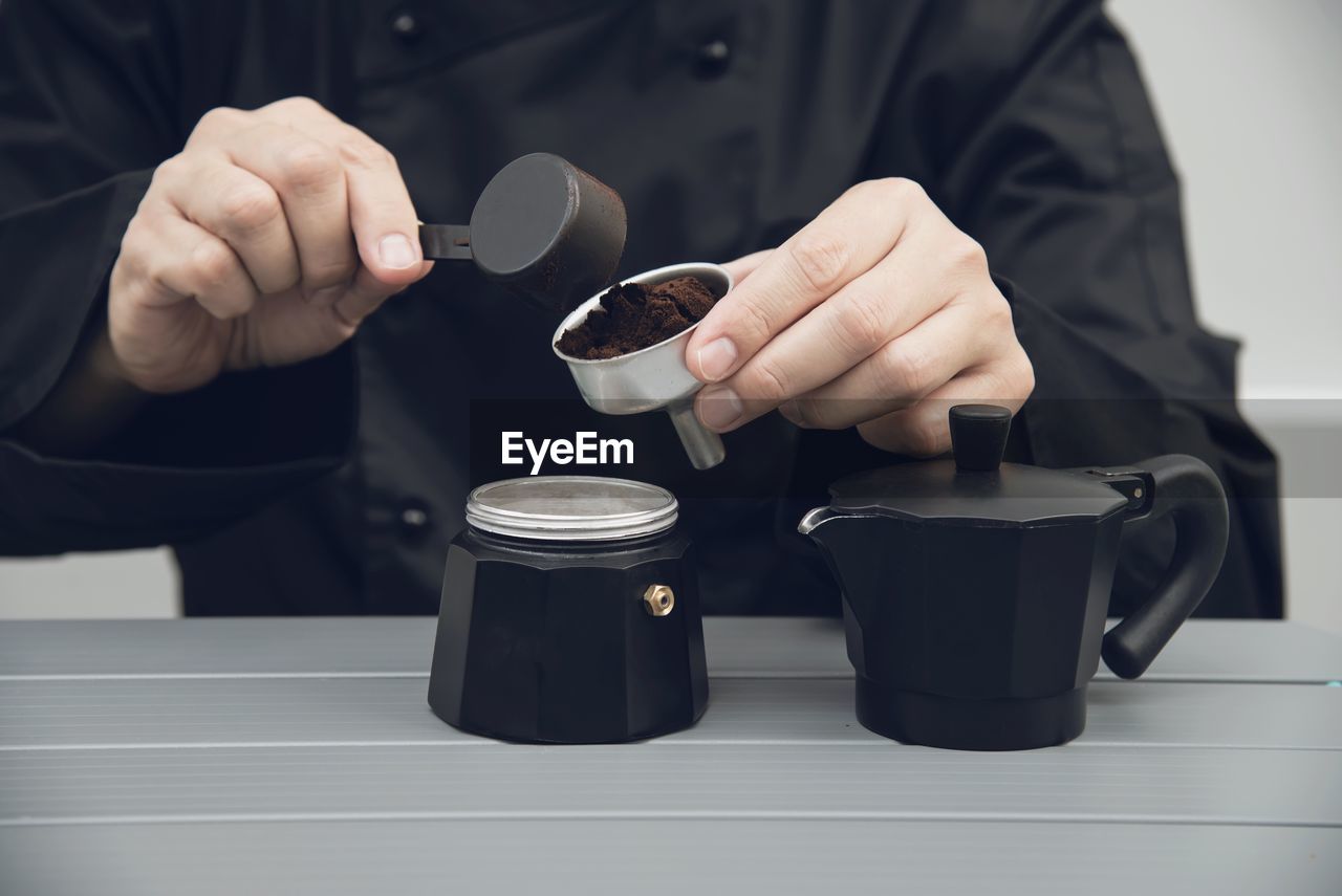 Asian barista is making hot coffee using moka pot